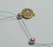 Two beads and a clasp strung onto a thread